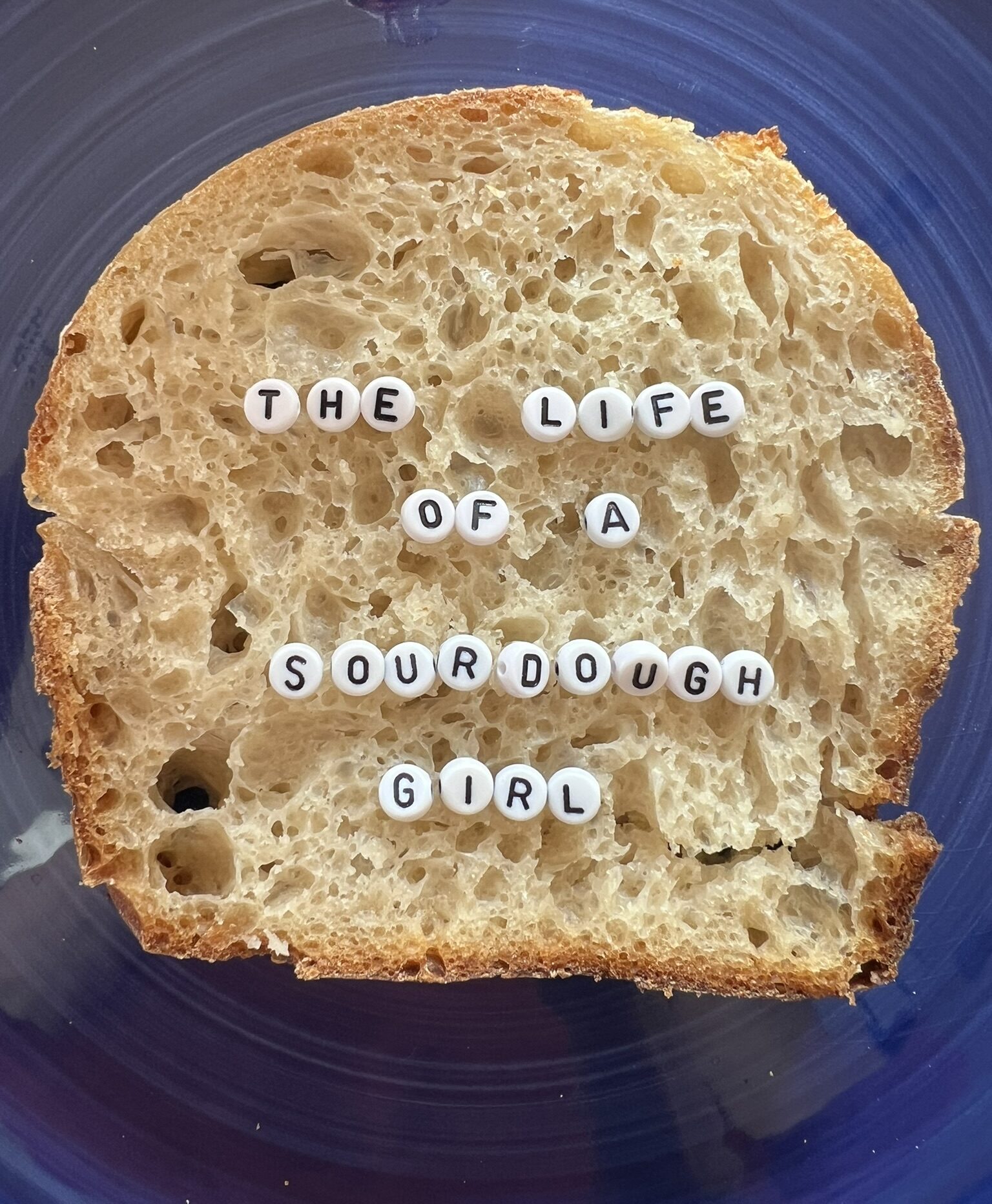 A sourdough bread slice with letter beads that spell out The Life of a Sourdough Girl