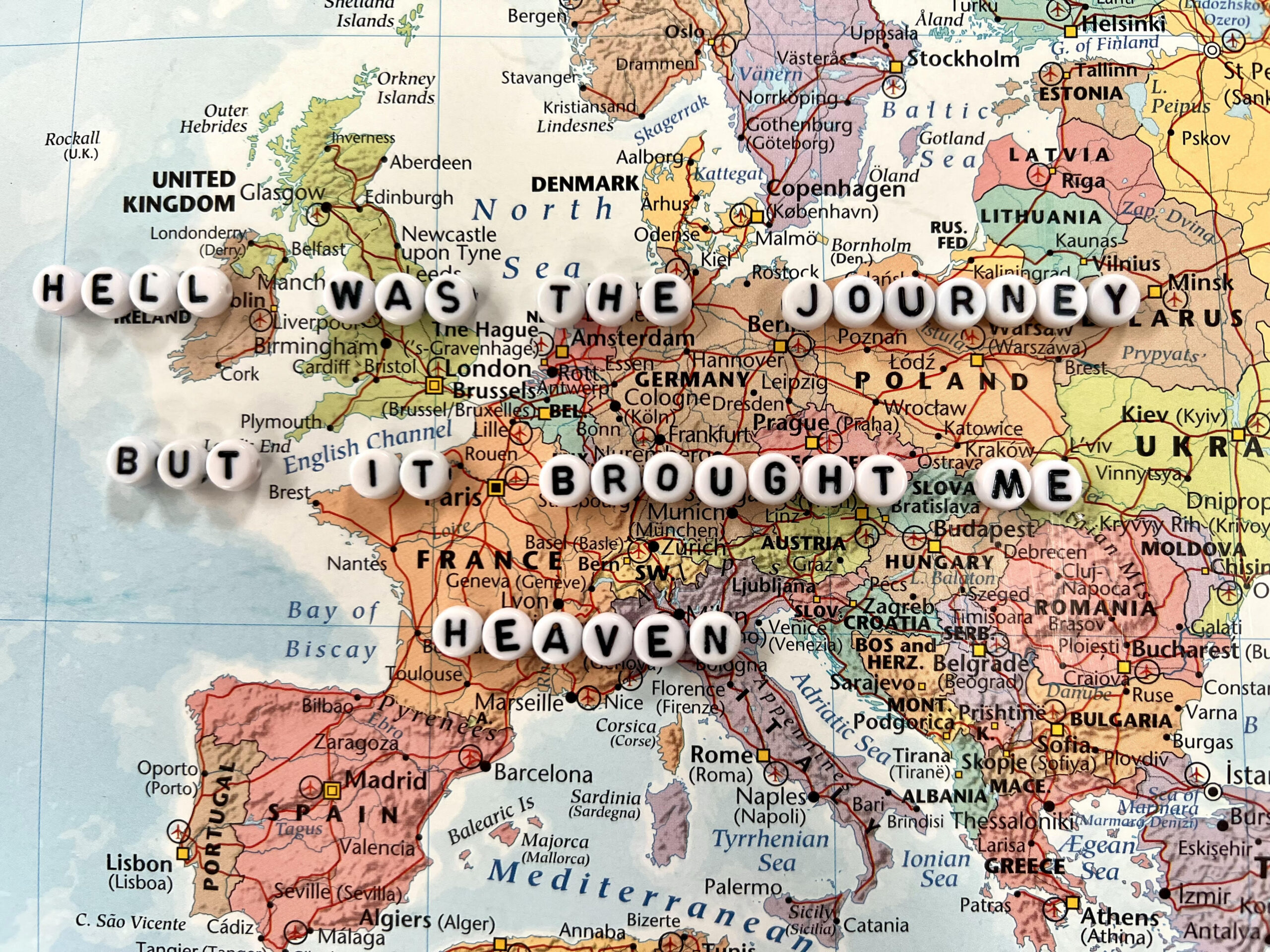 A map of Europe with the phrase 'hell was the journey but it brought me heaven' spelled out in white letter beads across the centre.
